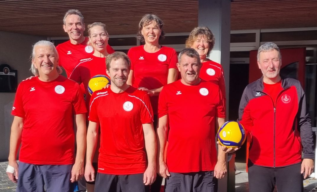 8 lachende Waldenbucher Volleyballer in ihren roten Trickots in der Sonne vor dem Panoramabad in Freudenstadt.
