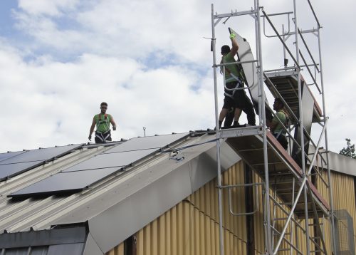 Das Bild zeigt die Arbeit an der PV-Anlage am Hallendach: Jedes der 62 Module wiegt 25,3 Kilogramm